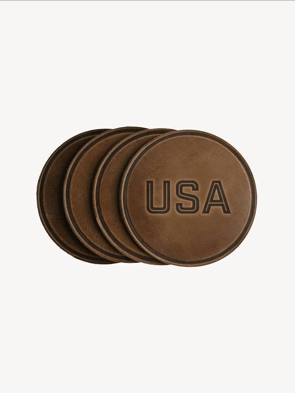 Set of four brown leather coasters with 'USA' engraving on a white background